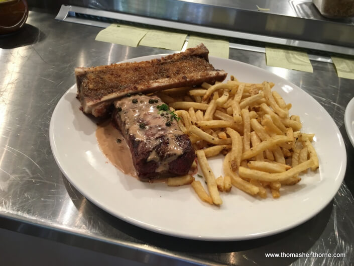 photo of steak au poivre with marrow and fries at le comptoir