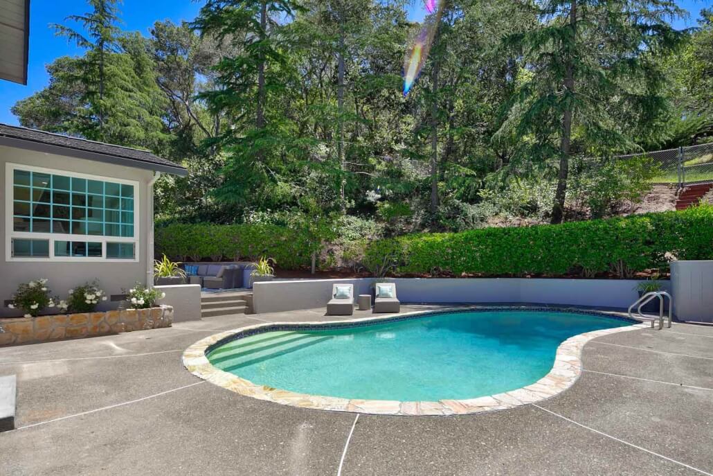 Swimming pool with hedge behind and home to left t 501 Alameda de la Loma in Novato