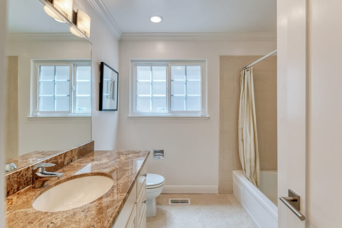 upstairs bathroom with shower tub combo and stone countertop