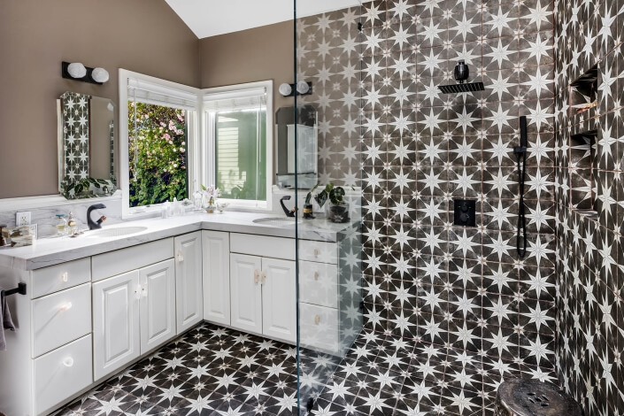 Primary bathroom with dual sinks and walk in shower with geometric tile