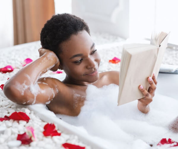 women in spa bathtub with flowers reading