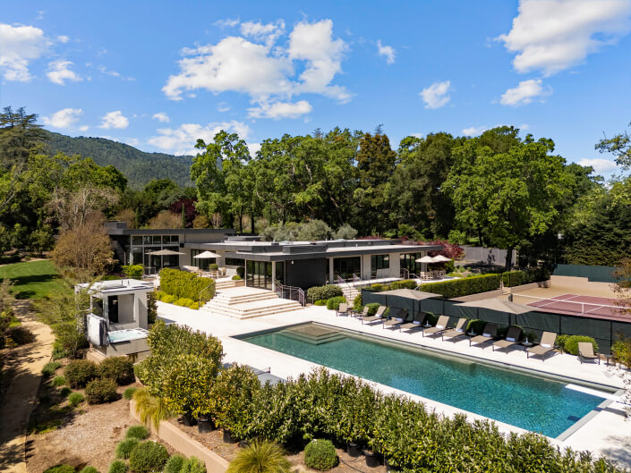 aerial view of home and swimming pool area with tennis court in background