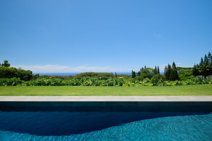 A pool with grass and trees in the background.