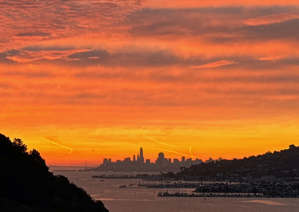 IMG_4135 From De Silva Island: Sunrise over the San Francisco skyline, with orange and yellow hues in the sky, silhouetted buildings, the bay, and hills framing the city.