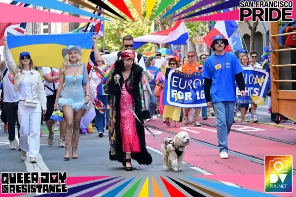 SF Pride photo Diverse group at San Francisco Pride with Ukraine flag, banners “EUROpe for LIGHTS” & “QUEER JOY IS RESISTANCE,” dog, rainbow frame.