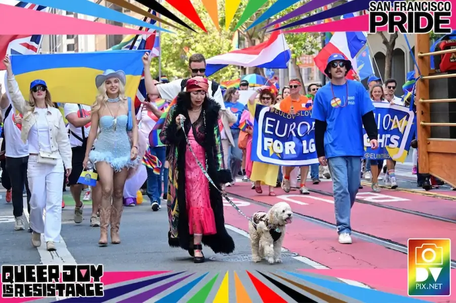 Diverse group at San Francisco Pride with Ukraine flag, banners “EUROpe for LIGHTS” & “QUEER JOY IS RESISTANCE,” dog, rainbow frame.