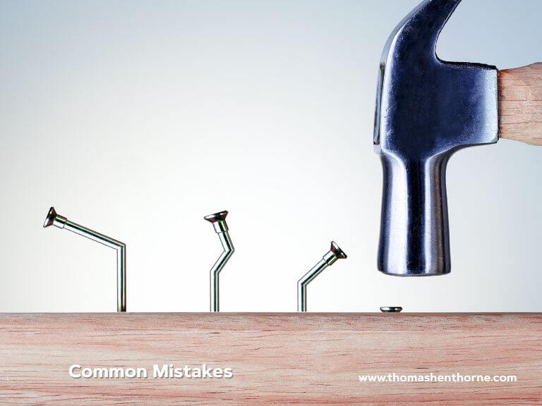 common mistakes design canva A hammer poised above a nail, ready to strike, while three bent nails are embedded in the wood below. The words Common Mistakes appear on the image, with a website link displayed at the bottom right corner.