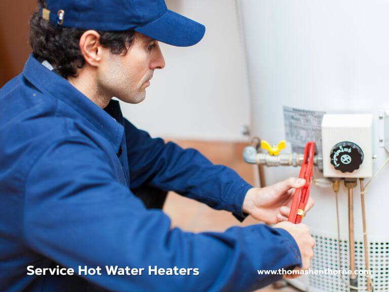 A technician in a blue uniform uses a red wrench to adjust a hot water heater. The words "Service Hot Water Heaters" are displayed, with the website www.thomashenthorne.com shown in the bottom right corner.
